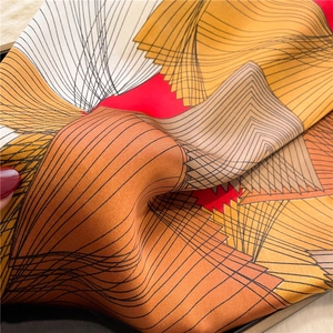 Detail of silk-like square scarf showing smooth texture and geometric line patterns