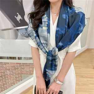 Detail shot of a blue and white gradient tie-dye silk scarf on a white blazer outfit
