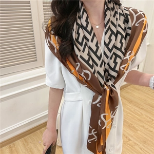 Detail of silk-like square scarf with vintage geometric prints on a model in white dress