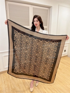 Detail view showing black and gold monogram floral patterns on large square silk scarf