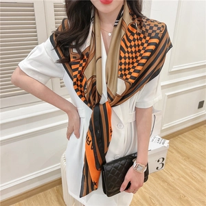 Detail of vintage patterned silk scarf with orange and black patchwork print on shoulder