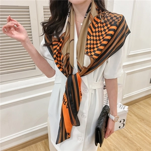 Detail of geometric orange and brown silk scarf worn by model as a stylish necktie