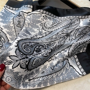 Close-up of black and white paisley silk scarf showing elegant satin texture and patterns