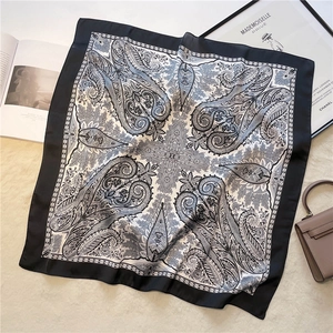 Vintage paisley print silk square scarf in black and white displayed on plush background
