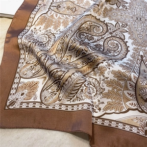 Close-up of silk-textured paisley print scarf with brown borders on a soft fur background
