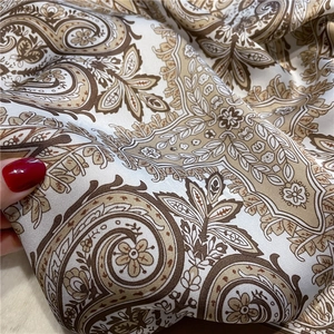 Detailed macro view of retro paisley print silk scarf with smooth glossy texture
