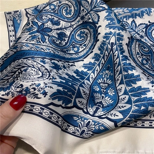 Detailed close-up of smooth royal blue paisley silk scarf with soft fabric texture