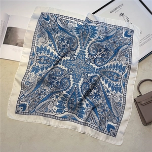 Detailed view of square silk scarf with navy paisley pattern on white background