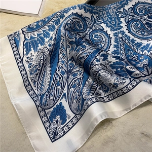 Detailed close-up of paisley pattern silk scarf on cozy beige plush background