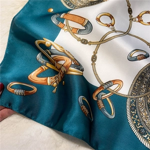 Close-up of peacock green silk scarf with vintage chain and equestrian buckle pattern
