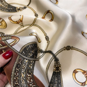 Detail of silk-like scarf featuring golden chain patterns and elegant color blocking