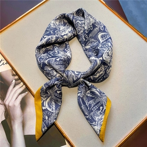 Détail d'un foulard en soie rétro noué en boucle avec imprimé bleu et bord jaune