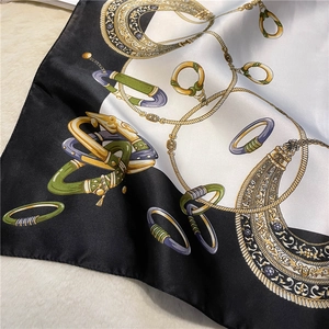 Detail of silk satin scarf featuring luxury gold chain and jewelry print with rolled edges