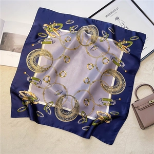 Detailed macro view of silky square scarf with blue borders and golden chain patterns