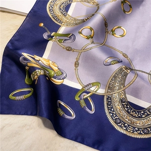 Detail of luxury silk scarf featuring golden chain patterns with navy and lilac panels