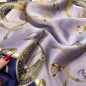 Close-up of lilac silk scarf featuring vintage chain prints and satin texture