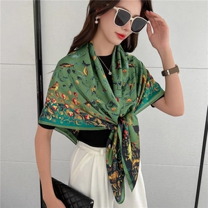 Dettaglio di un lussuoso foulard in seta verde con stampe di uccelli e fiori su modella