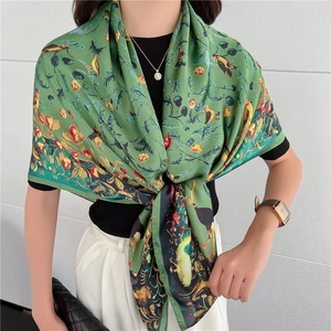 Dettaglio di un elegante foulard in seta con stampa floreale e uccelli e pochette classica