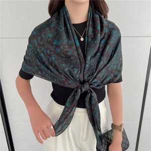 Dettaglio dell'elegante sciarpa in seta paisley drappeggiata sulle spalle con riflessi