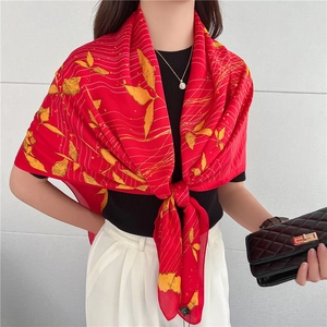 Vista dettagliata del foulard in seta rossa leggera annodato su un top nero a girocollo