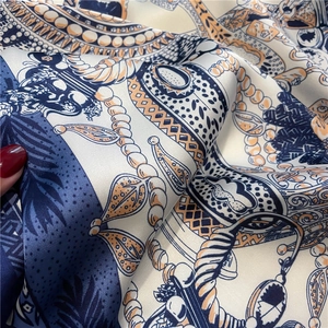 Nahaufnahme von Seidenschal mit Vintage-Ketten und Blumenmustern auf blauem Stoff