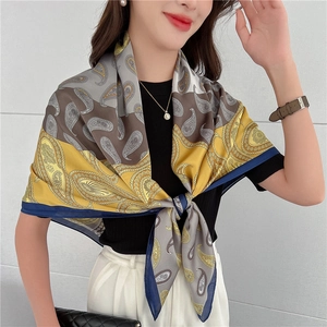 Dettaglio di un foulard quadrato effetto seta con motivi paisley e trama levigata