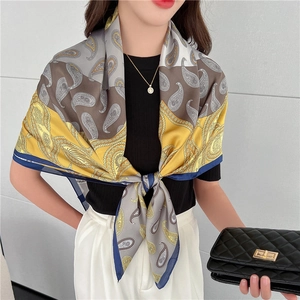 Dettaglio della sciarpa in seta paisley gialla e grigia abbinata a un maglione nero