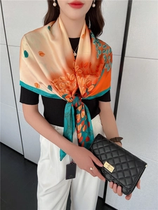 Dettaglio di un grande foulard in seta con foglie arancione caldo e verde vibrante