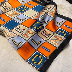 Close-up of checkered silk scarf featuring artistic letter prints and hand-rolled edges