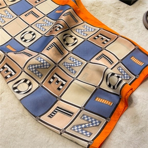 Detail of colorful letter print silk scarf with orange border on plush background