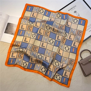 Detail of a 70cm square silk scarf with colorful geometric letters on a plush rug