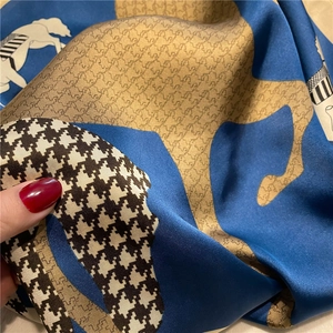 Detail of satin scarf featuring blue horse silhouettes and houndstooth pattern print