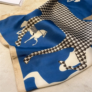 Close-up of silk-textured horse print scarf with houndstooth pattern and gold trim