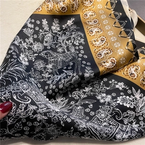 Détail macro du motif cachemire et floral sur un foulard carré en soie satinée