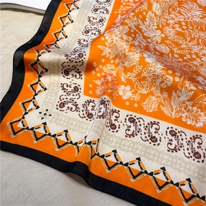 Détail d'un foulard en soie à motif paisley et fleurs sur fond en peluche douce
