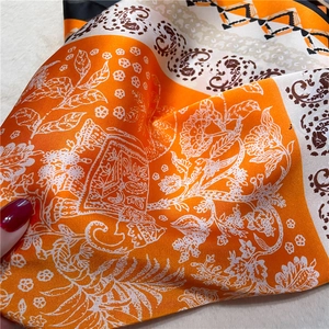 Gros plan détaillé d'un foulard en satin avec motifs paisley orange et fleurs élégantes