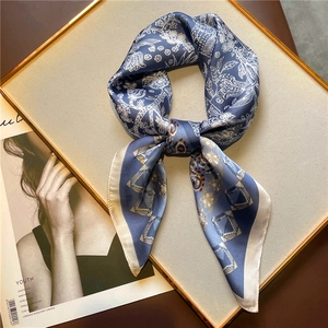 Détail d'un foulard en soie bleue avec motifs floraux vintage sur un plateau doré