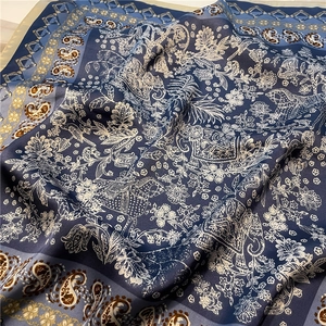 Vue détaillée d'un foulard en soie bleu foncé avec motifs paisley, chevaux et éléphants