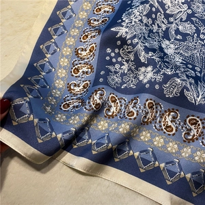 Détail d'un foulard en soie bleu avec motifs paisley et bordures roulées
