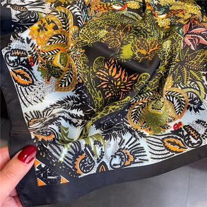 Détail d'un carré de soie avec imprimé tropical de fleurs et d'oiseaux et bords roulés