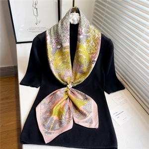 Détail de la texture du foulard en soie avec motifs floraux et boucle en perles