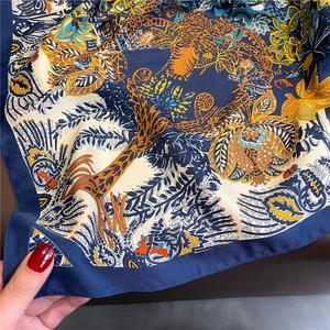Gros plan d'un foulard en soie avec des motifs complexes de jungle et de fleurs