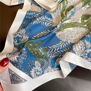 Détail d'un foulard en soie à motif cachemire bleu et vert avec une couture précise