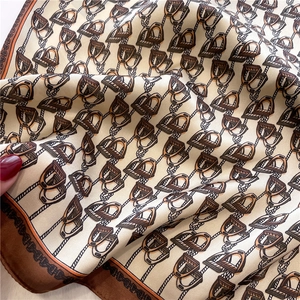 Close-up of luxury silk scarf showing intricate equestrian patterns and smooth texture