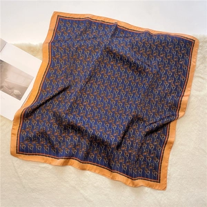 Navy blue equestrian silk scarf with orange border on a white fur rug background