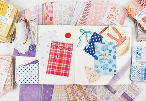 Draufsicht auf buntes Deko-Scrapbook-Papier mit Blumen- und Karomustern für Bastelarbeiten
