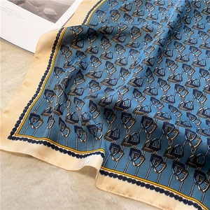 Detail of luxury silk scarf with equestrian stirrup pattern on soft plush carpet