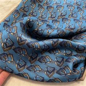 Close-up of luxury dark blue silk scarf featuring classic equestrian stirrup patterns