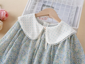 Détail de robe fleurie fille avec col à pois, bords en dentelle et nœud papillon blanc
