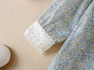 Détail des manches d'une robe fleurie pour filles avec pois bleus et bordure dentelle